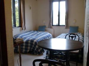 Habitación con cama, mesa y sillas. en ペンション木もれ日, en Ito