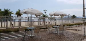 twee tafels en stoelen met parasols op een terras bij het strand bij Verdadeiro Pé na Areia in Santos
