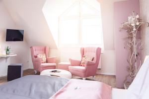 a bedroom with pink chairs and a bed and a window at Hotel Wulff in Bad Sassendorf