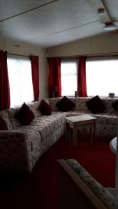 a living room with a couch and red curtains at 6 berth on Northshore En-suite Sunnyside in Winthorpe