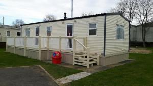 a small white house with a porch and a yard at 6 berth on Northshore En-suite Sunnyside in Winthorpe