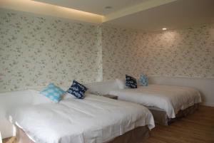 two beds in a room with floral wallpaper at Pisces Garden B&B in Checheng