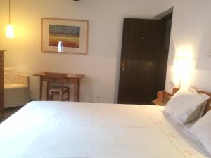 um quarto com uma cama branca e uma mesa em Casa Rural Hosteria Cantarranas em Cuacos de Yuste