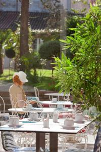 a woman sitting at a table in front of a table with cups at Grand Hôtel Niort Centre in Niort +45 photos