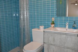 W wyłożonej niebieskimi kafelkami łazience znajduje się toaleta i umywalka. w obiekcie Canary Islands getaway w mieście Caleta De Fuste