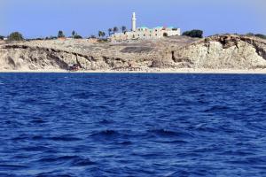 a lighthouse on an island in the middle of the ocean at Raphael Apartments in Herzelia 