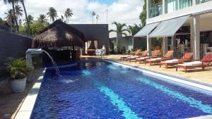 a swimming pool with a umbrella and chairs next to a building at Relais de Charme Boutique Hotel Pititinga in Rio do Fogo
