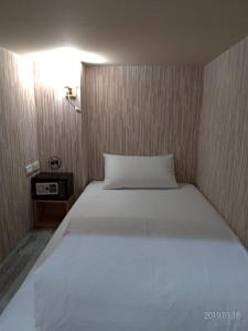 a white bed with a white comforter and pillows at Old Door Hostel & Bar in Taipei
