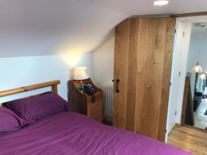 a bedroom with a purple bed and a wooden door at The Stables @ The Old Vicarage in Pendeen