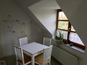 a dining room with a white table and four chairs at Ferienwohnung Holtenau in Altenholz