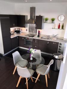Blue Sky Apartments @Wallis Square, Farnborough في فارنبورو: مطبخ مع طاولة وكراسي ومغسلة
