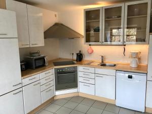 a kitchen with white cabinets and a sink and a stove at Ferienwohnung Holtenau in Altenholz +7 photos