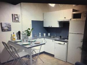 uma pequena cozinha com uma mesa e um frigorífico branco em Terrasse tropézienne centre Nimes em Nîmes