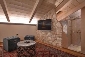 Zimmer mit einer Steinmauer, einer Dusche und einem Tisch in der Unterkunft KAMARES Historic Boutique Hotel & Spa in Ioannina