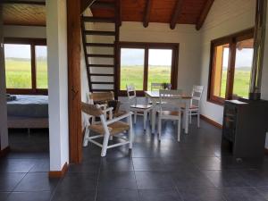 Un comedor con mesa y sillas y ventanas. en La Ranita Negra, en La Paloma