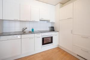 Biała kuchnia z białymi szafkami i zlewem w obiekcie LAAX Homes - Capolgarten 3,7 w mieście Flims