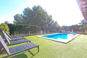 a backyard with a swimming pool with two chairs and a bench at Villa Puerto Adriano in El Toro