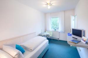 1 Schlafzimmer mit 2 Betten und einem Schreibtisch mit einem TV in der Unterkunft Hotel Kleiner König in Schwangau