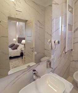 FLOS Guest House في لوتشرا: حمام أبيض مع حوض ومرآة
