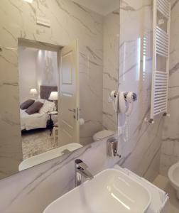 biała łazienka z umywalką i lustrem w obiekcie FLOS Guest House w mieście Lucera