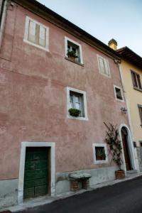 un bâtiment rose avec une porte et des fenêtres vertes dans l'établissement La casa rosa, à Vitiano
