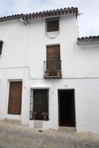 Edificio blanco con 3 ventanas y balcón en Casa La Tinaja, en Grazalema