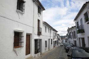 un vicolo con edifici bianchi e auto parcheggiate in una strada di Casa La Tinaja a Grazalema