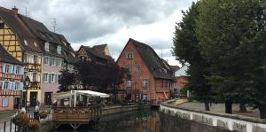 a river in a town with houses and a boat at BORD EAU Guest House in Colmar