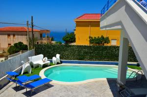 ein Pool mit Stühlen und ein gelbes Gebäude in der Unterkunft Villa con piscina Alcamo Marina in Alcamo