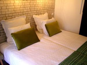 a white bed with two green pillows on it at Small Loft in Cascais