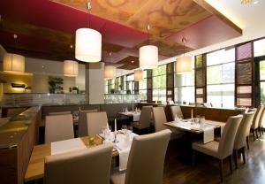 a dining room with tables and chairs and windows at Steigenberger Dortmund in Dortmund