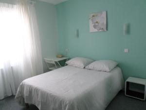 1 dormitorio con cama blanca y ventana en Hôtel du Littoral, en Camoël