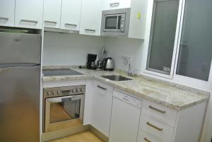 a white kitchen with a sink and a microwave at Los Alamos in Torremolinos