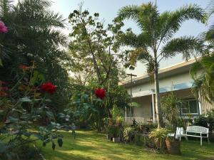 a house with palm trees and flowers in a yard at Better Weather Homestay in Pak Chong