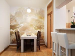 a dining room with a table and a painting of roses at Apartman KEJ free parking in Kraljevo