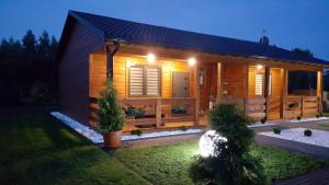 a small wooden cabin with a garden in front of it at Domki Kamila in Grzybowo