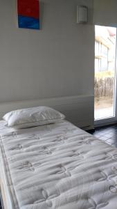 a white bed in a room with a window at Malibu Beach in Koksijde