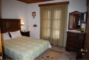 a bedroom with a bed and a dresser and a television at Petrino in Megalo Chorio