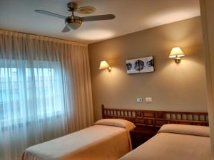 a bedroom with two beds and a ceiling fan at Hotel Xeito in Combarro