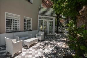 a patio with white chairs and a couch and windows at Villa Norma in Milano Marittima