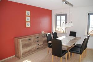 comedor con pared roja, mesa y sillas en Gutshof Lesch, Fewo3 OG links en Chemnitz
