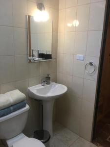 a bathroom with a sink and a toilet and a mirror at Las Cornizas de Catarpe in San Pedro de Atacama