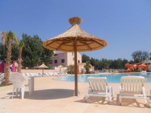 a patio with two chairs and a umbrella next to a pool at Mobil'home Valras in Valras-Plage