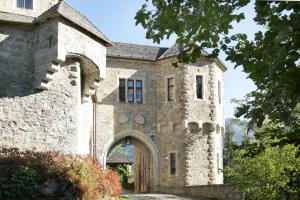 um antigo edifício de pedra com um arco em frente em Schloss Fischhorn am See em Bruck an der Grossglocknerstrasse