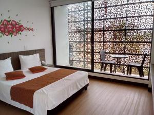 a bedroom with a bed and a table and a large window at Suite Sumapaz Hotel in Melgar