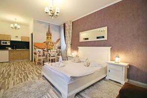 a bedroom with a white bed and a kitchen at Arhivelor Studios in Sibiu