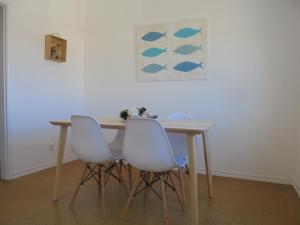 einen Tisch mit vier weißen Stühlen und ein Gemälde an der Wand in der Unterkunft BeachCity Guesthouse in Lagos