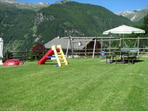 um parque infantil com mesas e um guarda-chuva na relva em Residence Fior di Roccia em Campodolcino