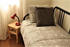 ein Bett mit einem Kissen und einer Lampe auf einem Tisch in der Unterkunft Casa Celeste Portugal in Vila Nova de Gaia