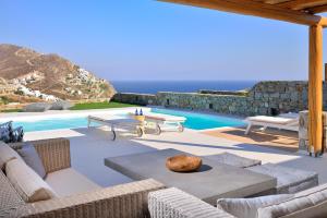 a patio with chairs and a pool with the ocean at Villa Kimothoe by Thalassa Residence Mykonos in Elia Beach